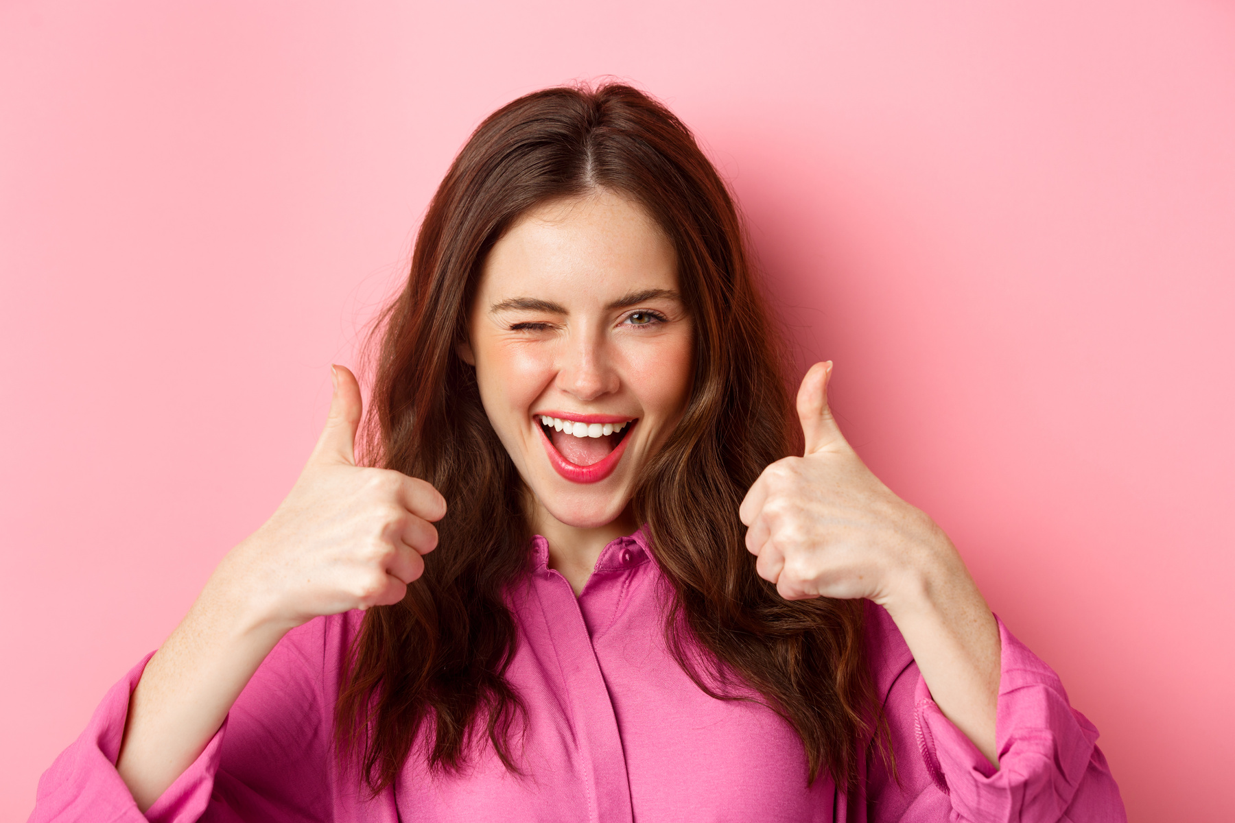 Cheeky Glamour Girl Winking at You and Shows Thumbs up, Praise Great Work, Good Choice, Standing over Pink Background